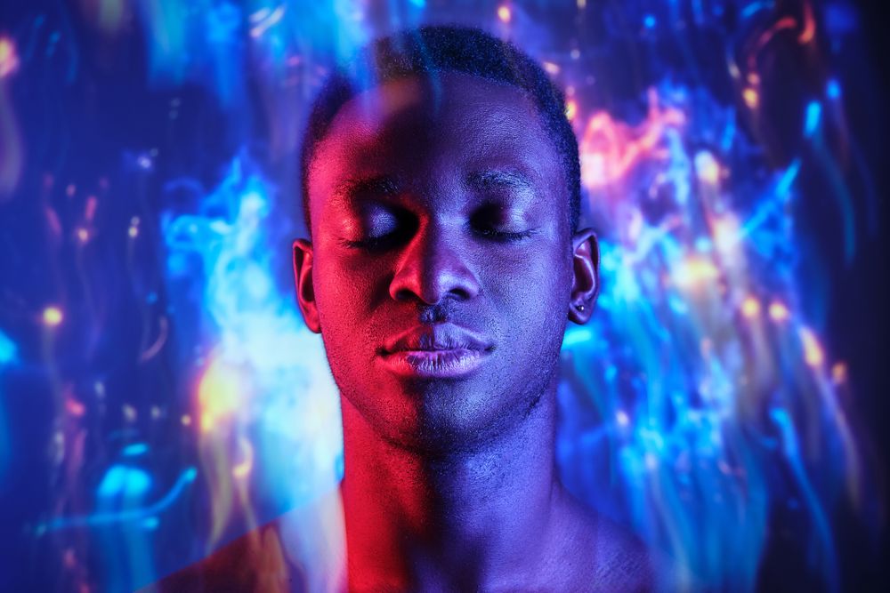 Emotionless Black man with eyes closed standing in blurred light