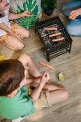 Top view of unrecognizable family grilling and eating sausages on barbecue