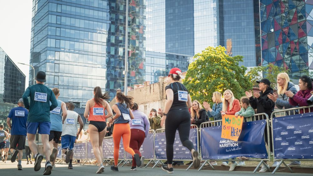 Back View: Diverse Group of Marathon Joggers Competing for the First Place, Running in a City Trail Audience Clapping