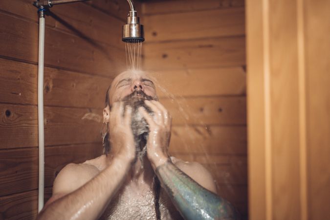 Man taking shower in wooden bathroom