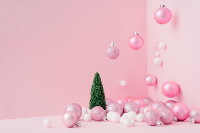 Baubles in a variety of pink shades in corner of pink room with Christmas tree