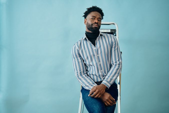 Man standing on a ladder against blue background