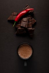 Chocolate near mug with hot drink and pepper