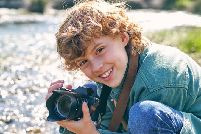 Smiling boy taking photo on coast near water