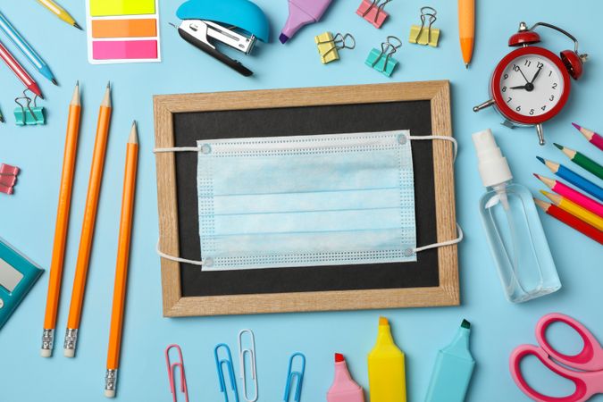 School supplies with medical mask and sanitizer on blue background