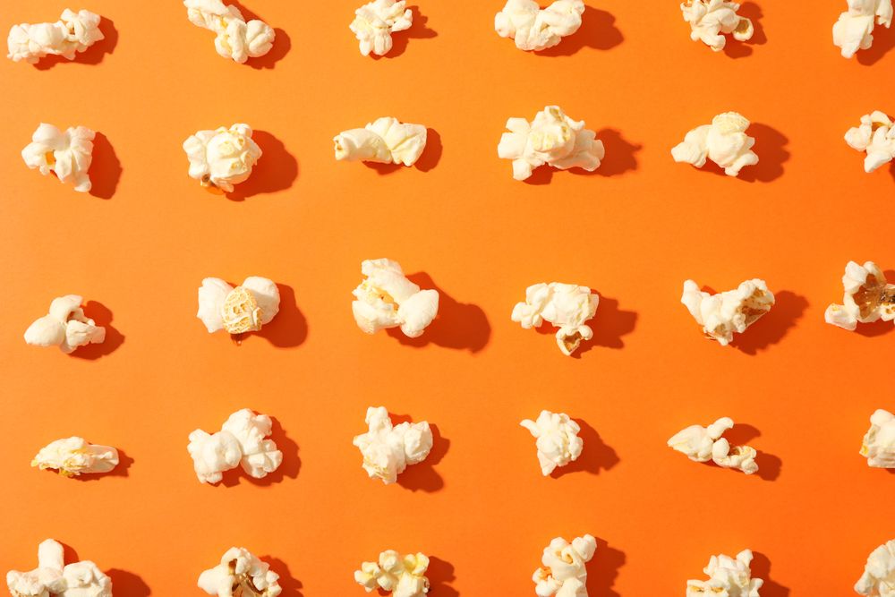 Flat lay composition with popcorn on orange background, closeup