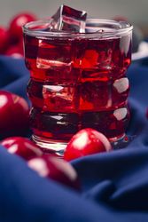 Red beverage near fresh fruits on cloth
