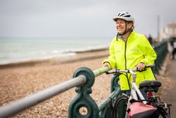 Happy mature woman enjoying coastal view from bike
