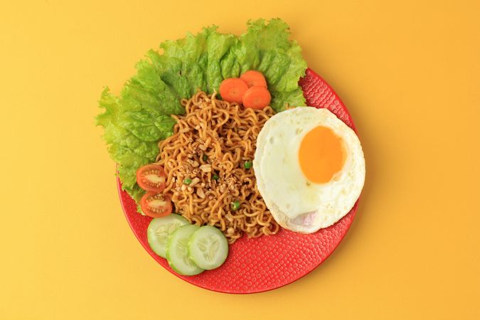 Top view of indomie goreng, Indonesian noodles and egg on yellow table