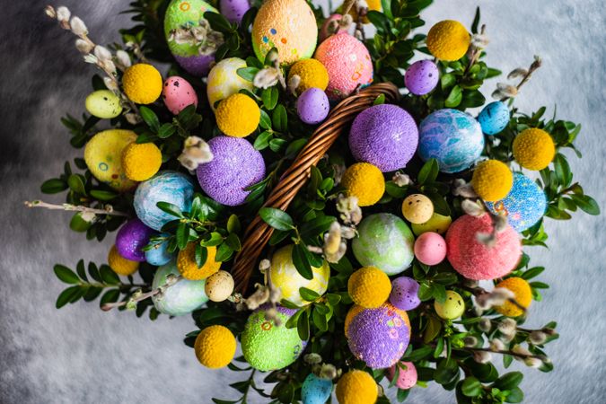 Top view of pastel Easter eggs & leaves in decorative basket