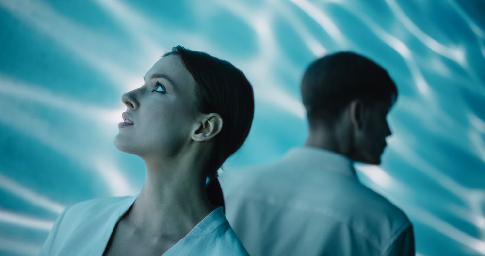 Talented Young Male and Female Dancers Engage in a Captivating Modern Dance Choreography, Dressed in Elegant White Attire, Performing Against a Digital Abstract Art Animation on a Big Screen