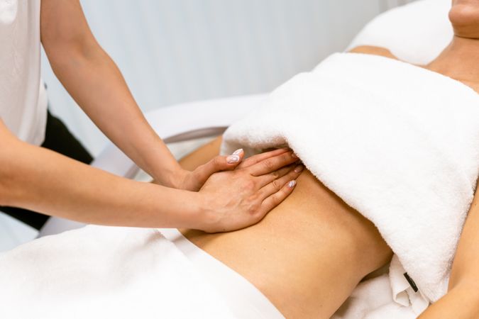 Massage therapist working on a female client’s stomach