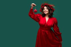 Happy woman in red dress holding Christmas ornament
