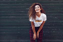 Happy Arab woman with curly hair leaning forward outside of metal security doors