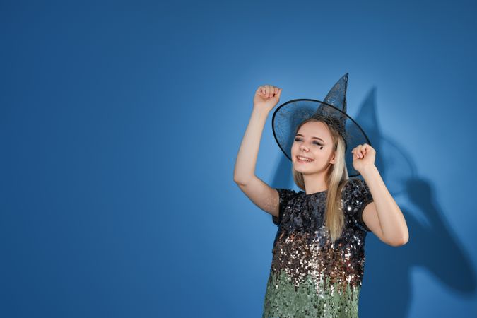 A woman in a Halloween costume is dancing at a party, on a blue background
