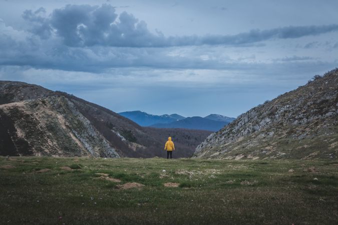 Anonymous traveler admiring hilly terrain on cloudy day