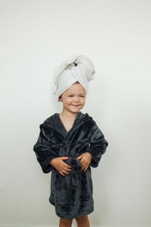 Smiling little girl wearing robe and towel on head