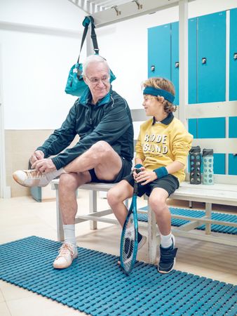 Older male trainer and boy preparing for tennis training