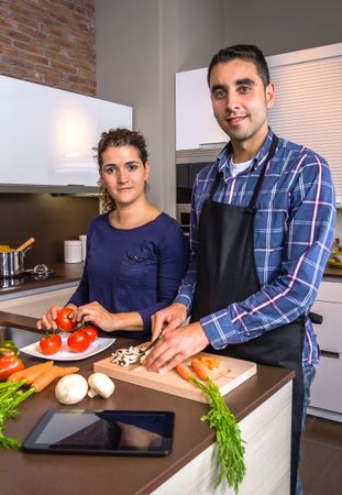 Portrait of couple cutting vegetables for dinner