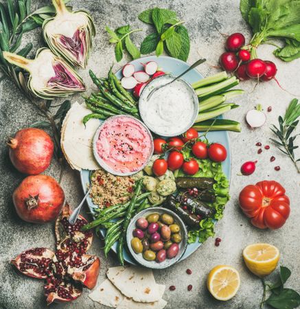 Fresh tray of snacks of fresh vegetables, olives, hummus, and dolmas with fresh herbs