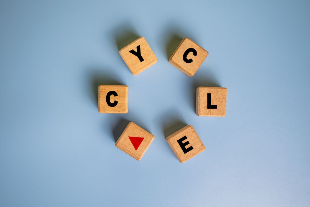 wooden blocks make round with cycle word symbol with red arrow isolated on blue background. cycling concept