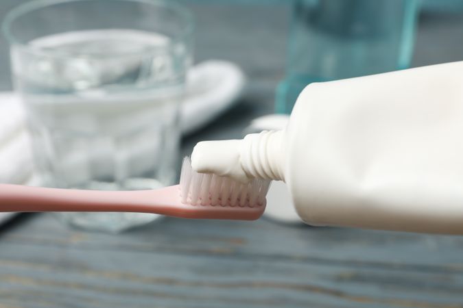 Toothbrush with toothpaste on background with dental care tools, close up