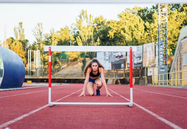 An athletic woman jumping hurdles on an athletics track.