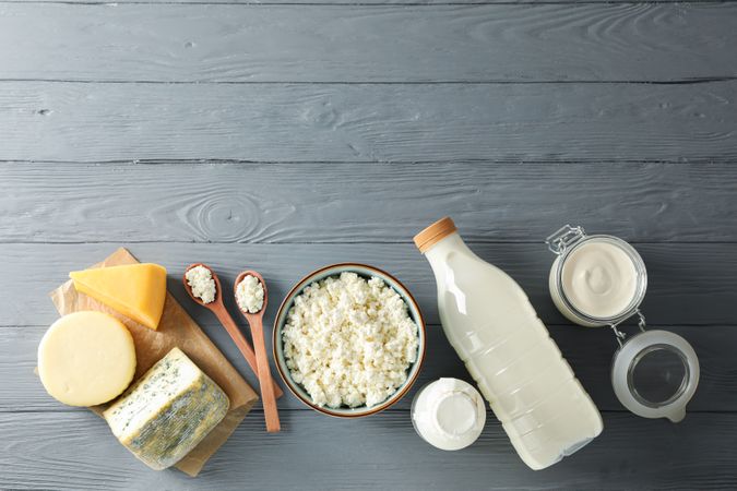 Flat lay. Different dairy products on grey wooden background, copy space