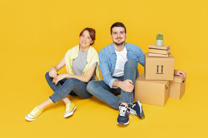 A couple with boxes, on a yellow background, the concept of moving.