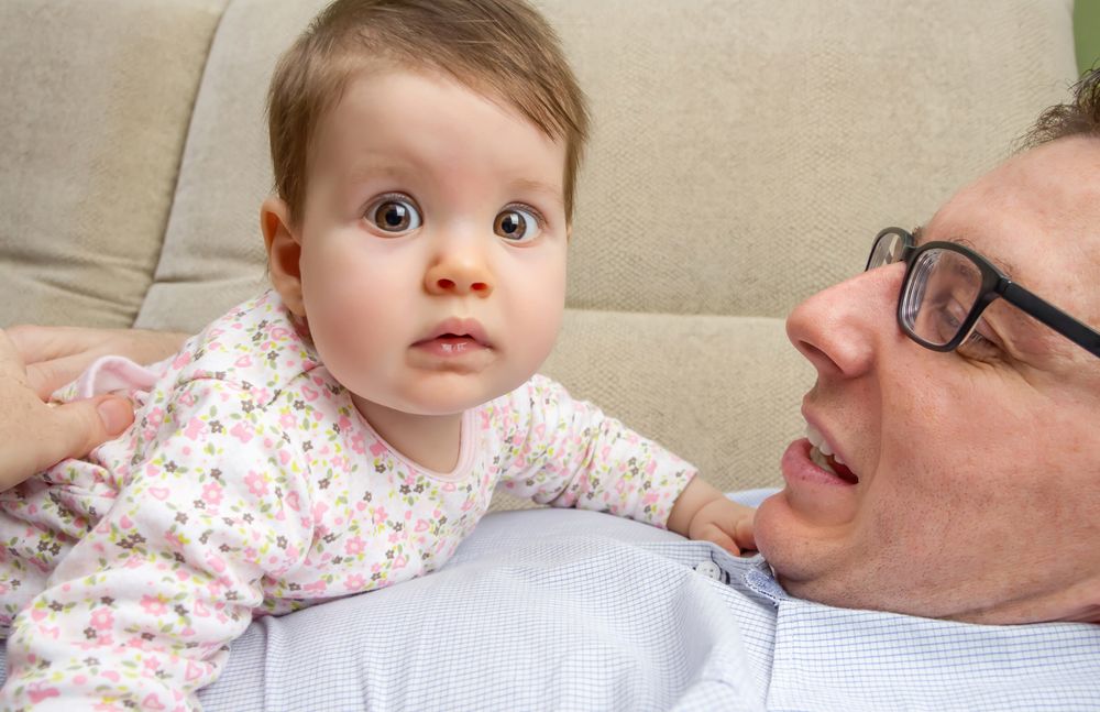Baby with big eyes sitting on father's chest