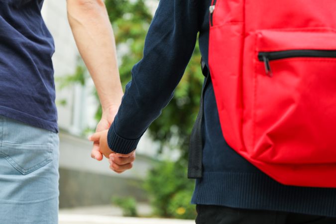 Man leads a boy to school against blurred background