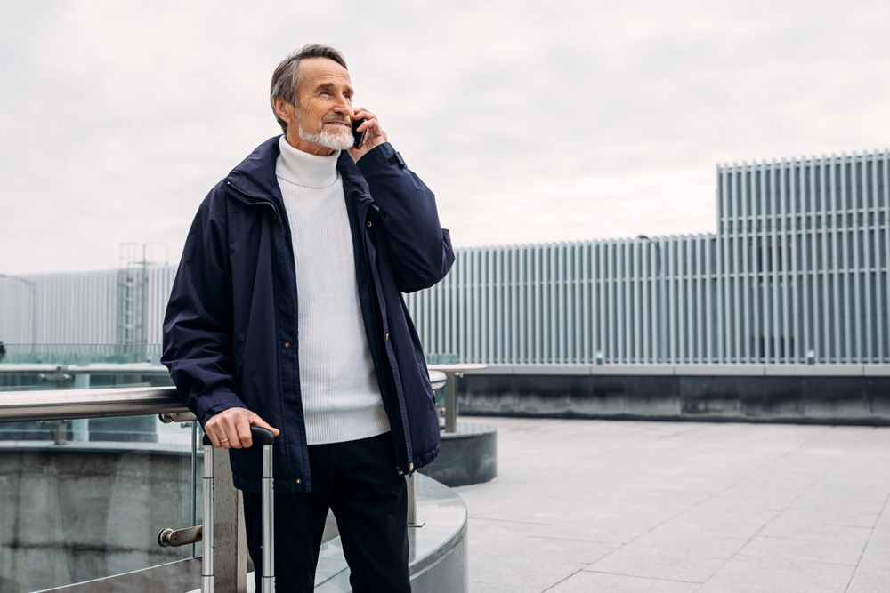 Man with cell phone and suitcase outside airport