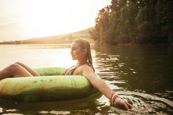 Side portrait of young woman in lake on inflatable ring