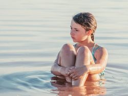 Teenage girl sitting in fresh water in sunny day
