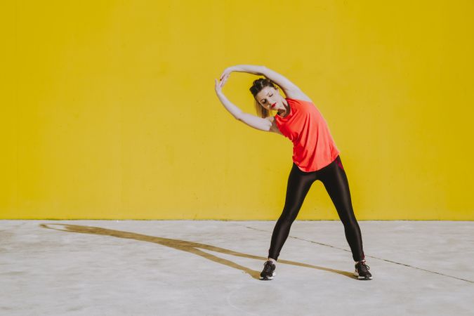 Woman stretching arms near wall