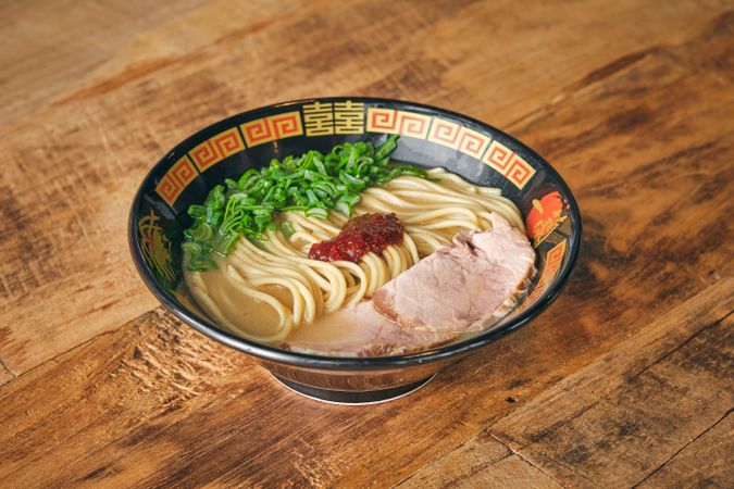 Delicious ramen with chopped scallions on table