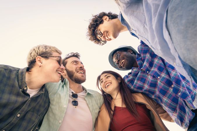 Diverse group of friends in a huddle, laughing and looking at each other.