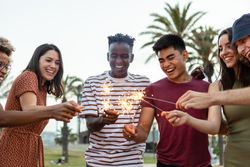 Happy young friends having fun holding sparkles at festival eve