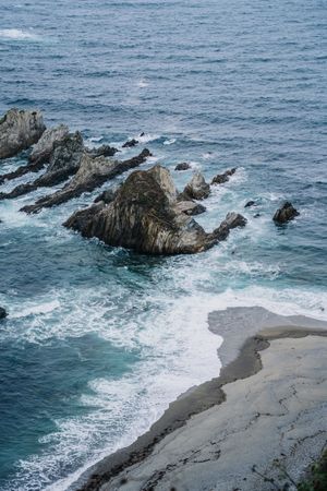 Rocky peaks surrounded by foamy water in windy day