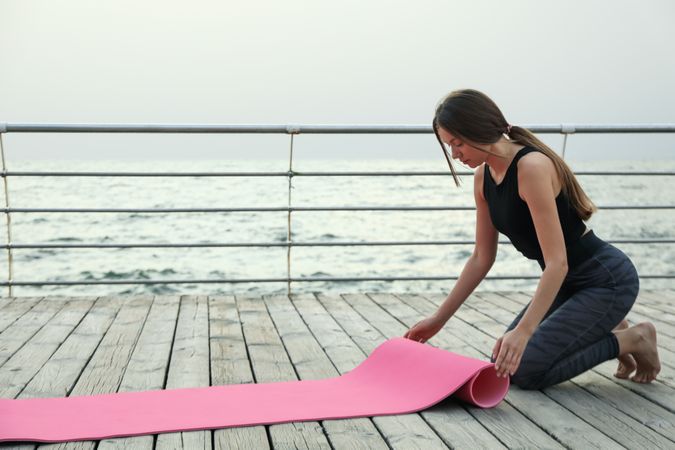 Young woman and yoga mat on wooden floor outdoors