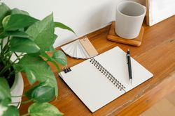 Office supplies on wooden shelves with notebook supplies, glasses and plants