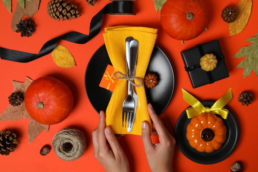 Cutlery in hands, pumpkins and leaves on red background, top view