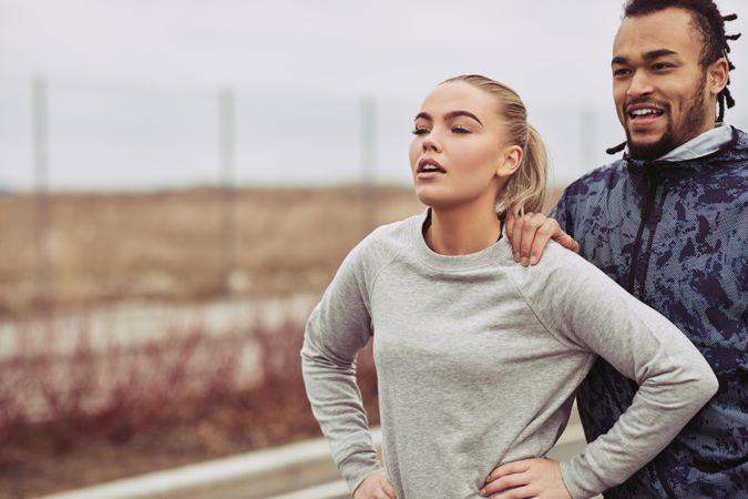 Attractive woman and man resting after jog outdoors