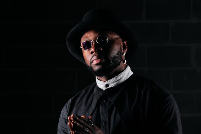 Black male model with prayer hands in stylish outfit looking at