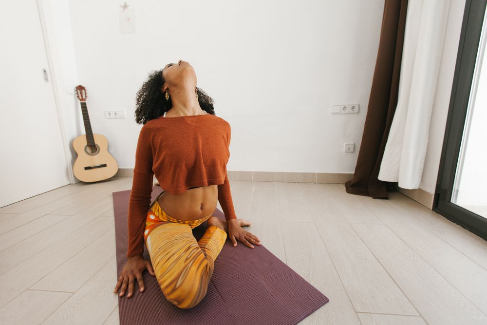 Sportive woman performing yoga pose in room
