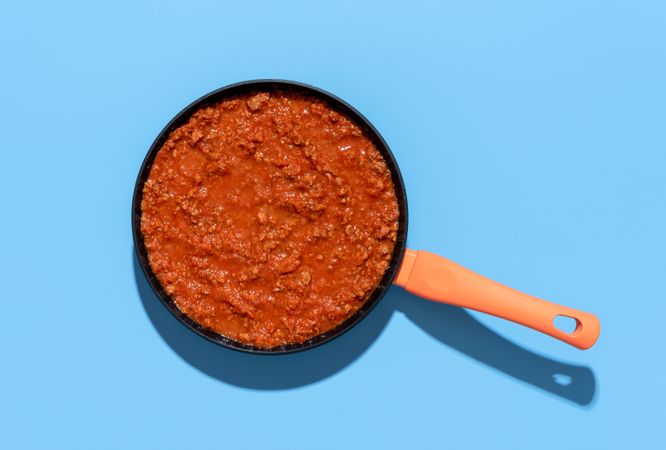 Pan with ragu sauce on a blue background
