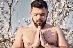 Shirtless man meditating in spring garden