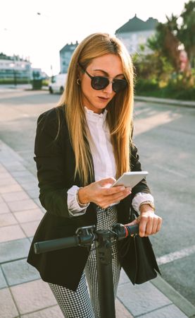 Businesswoman with e-scooter looking at cellphone