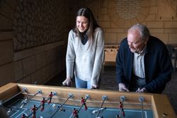 A granddaugther and his grandfather are playing table football game and having fun together