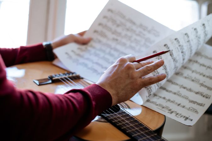 Man hands with sheet music playing guitar
